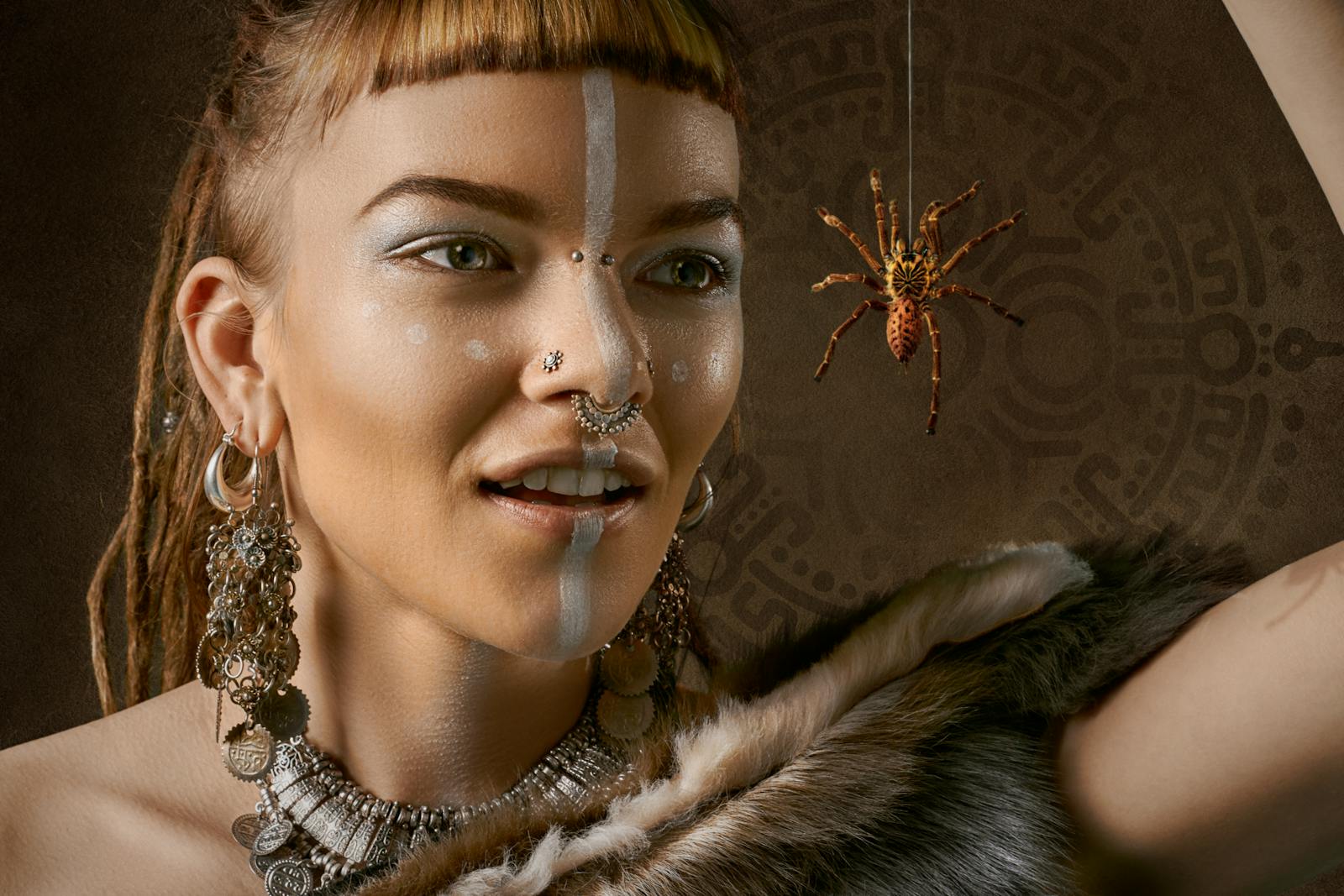 Close-up of a fashion model with tribal markings and a decorative spider.