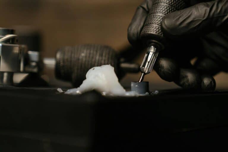 Detailed close-up of a tattoo needle with black gloves in a tattoo studio.