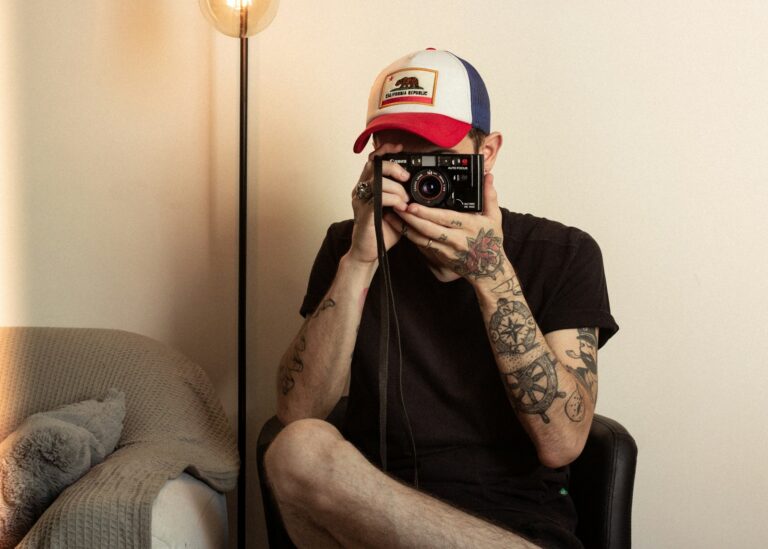 man sitting on chair using black DSLR camera