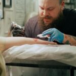 Professional tattoo artist creating arm tattoos in a studio setting. Capturing the art process.