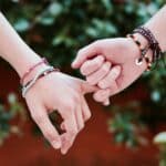 Two hands with colorful bracelets interlocked, symbolizing friendship and connection.