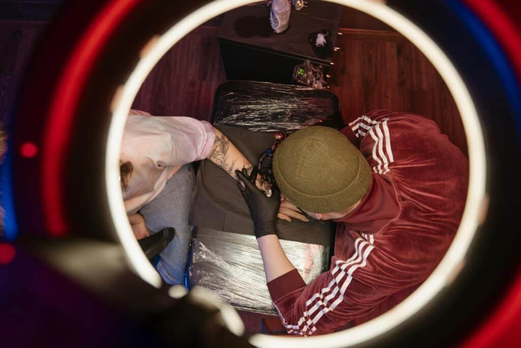 Overhead view of tattoo artist in studio, capturing creative process with ring light.
