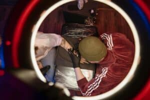 Overhead view of tattoo artist in studio, capturing creative process with ring light.