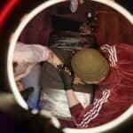 Overhead view of tattoo artist in studio, capturing creative process with ring light.