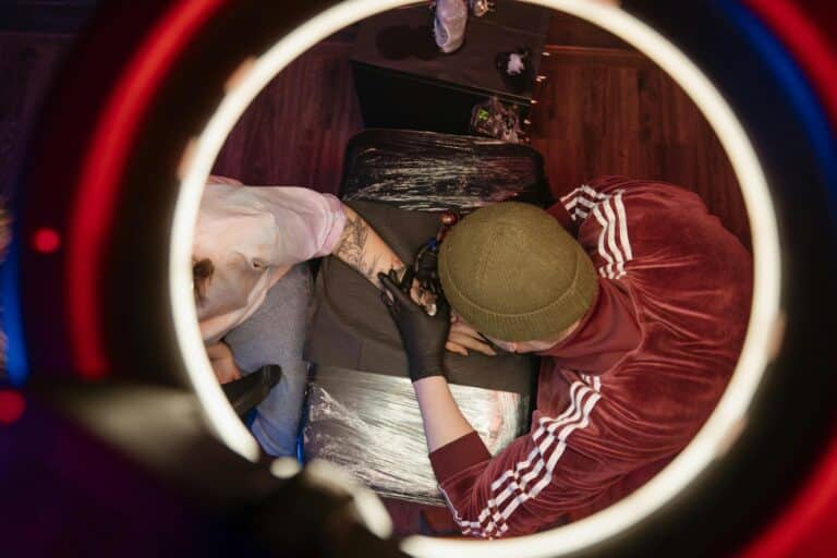 Overhead view of tattoo artist in studio, capturing creative process with ring light.