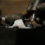 Detailed close-up of a tattoo needle with black gloves in a tattoo studio.