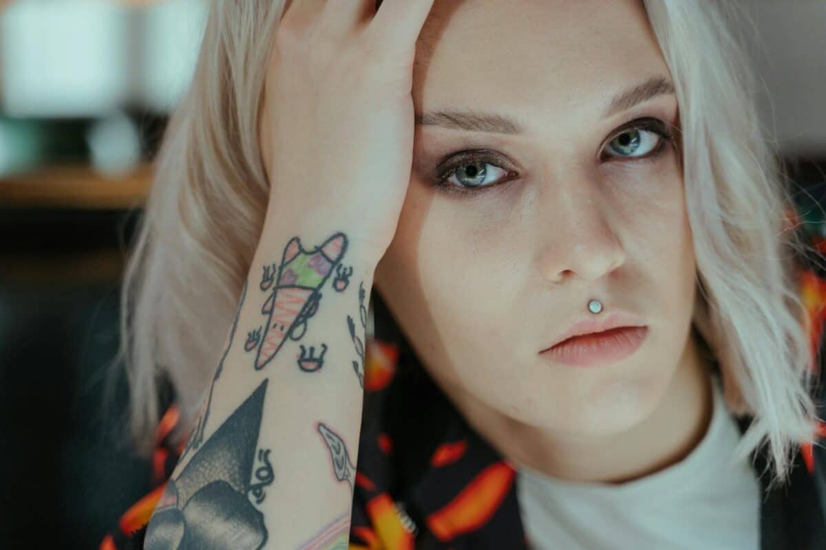 Close-up of a tattooed woman in deep thought with a focused expression.