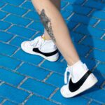 A person with tattoos standing on a blue brick sidewalk